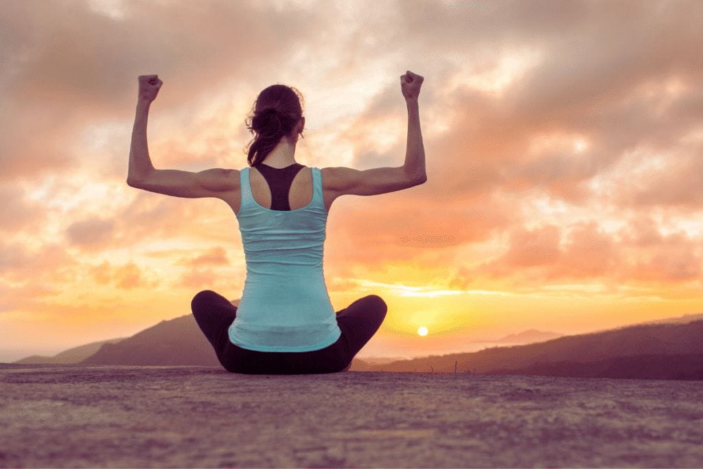 a strong woman sitting on a mountain