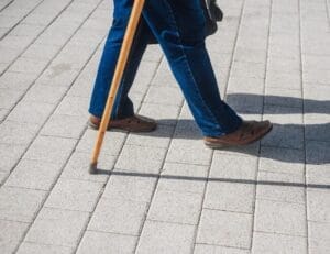 an older patient walking with the help of a walking stick